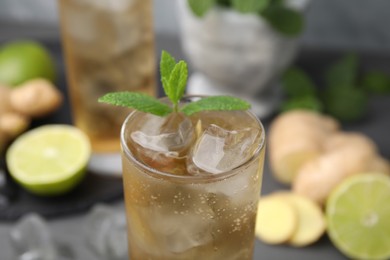 Photo of Glass of tasty ginger ale with ice cubes and mint on blurred background, closeup