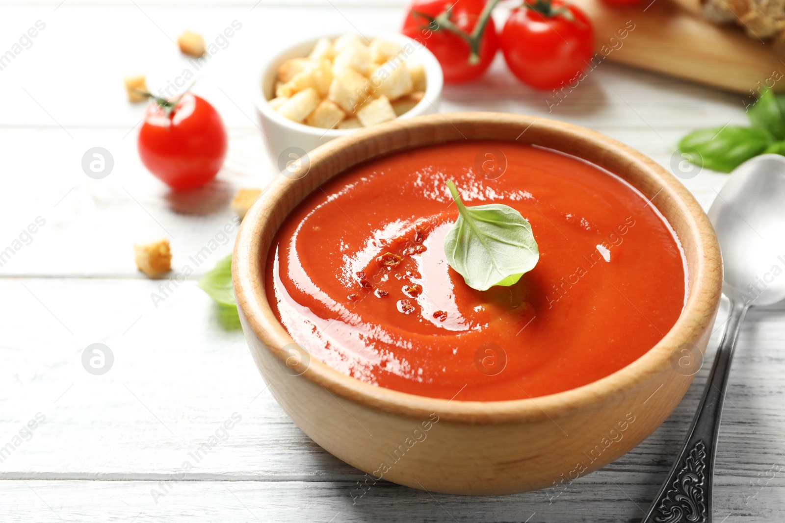 Photo of Bowl with fresh homemade tomato soup on wooden table