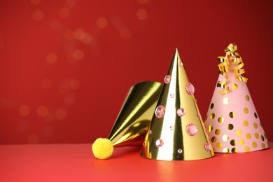 Photo of Party hats and serpentine streamers on red background, space for text
