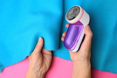 Photo of Woman with light blue scarf and fabric shaver on pink background, top view