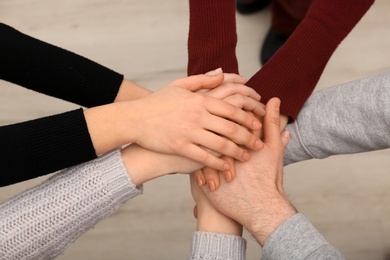 Photo of Young people putting their hands together indoors, closeup