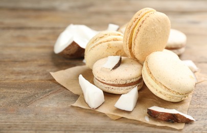 Photo of Delicious macarons and pieces of coconut on wooden table. Space for text