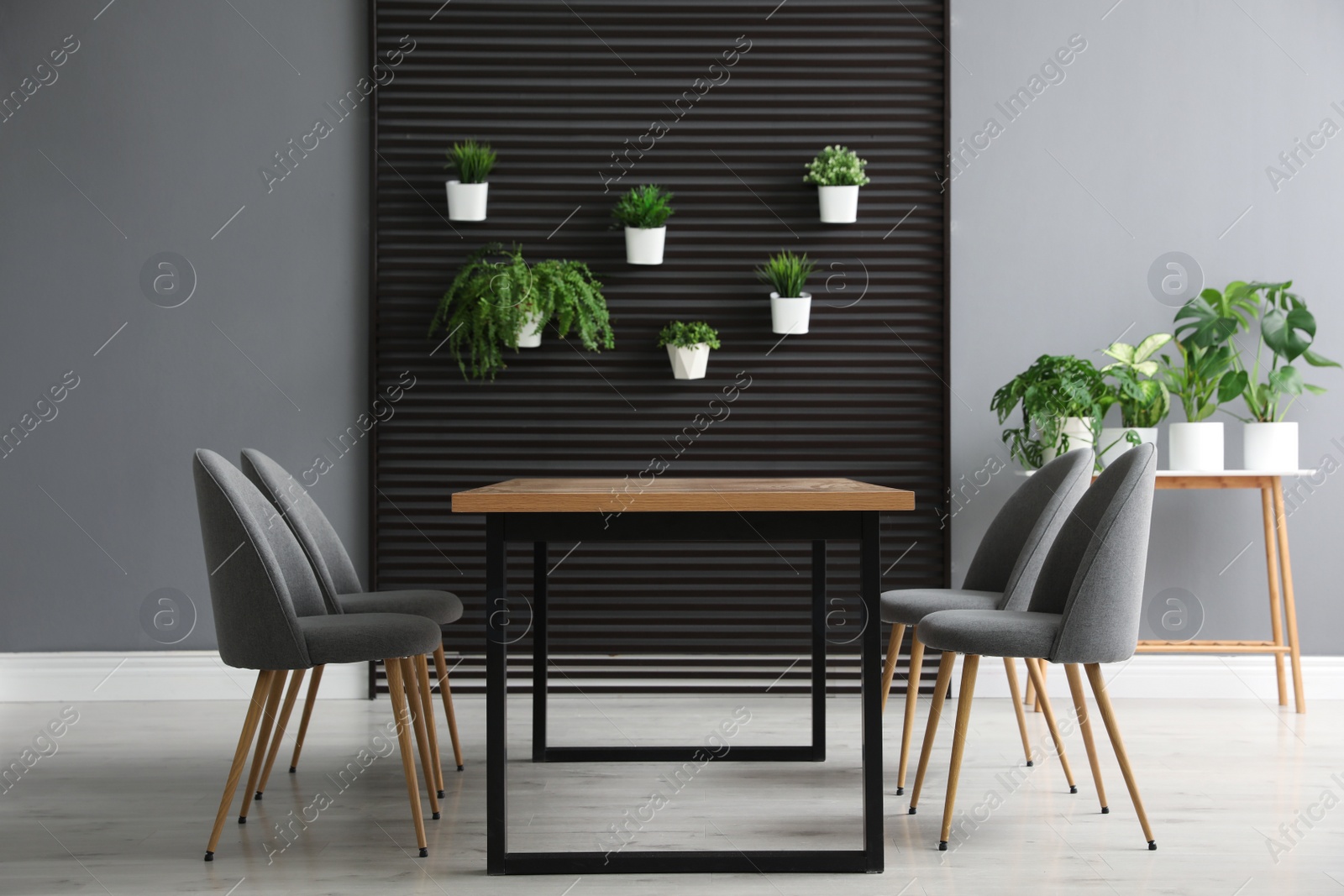 Photo of Stylish room with table, chairs and plants. Interior design