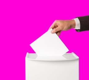 Image of Man putting his vote into ballot box on bright pink background, closeup