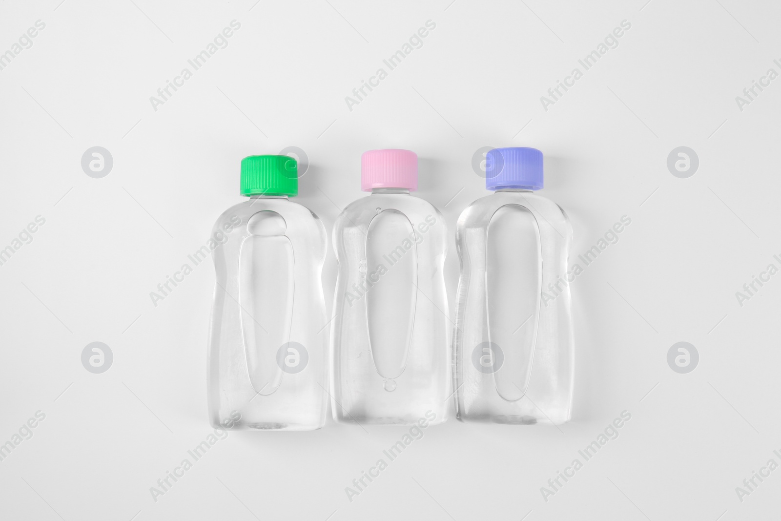 Photo of Transparent bottles with baby oil on white background, flat lay