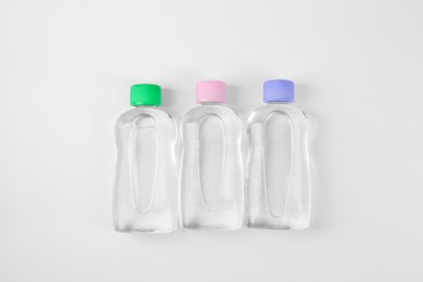 Transparent bottles with baby oil on white background, flat lay