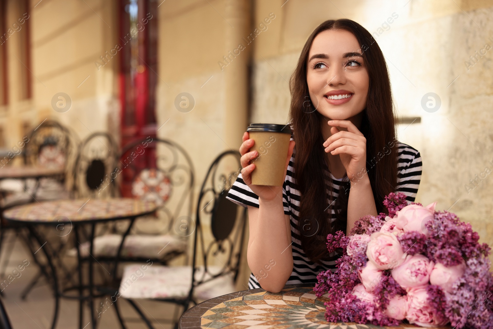 Photo of Beautiful woman with bouquet of spring flowers and coffee in outdoor cafe, space for text