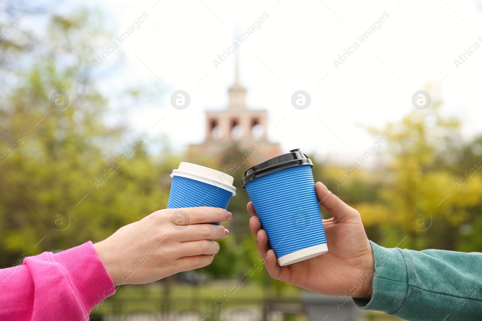 Photo of Couple with takeaway coffee cups on city street, closeup