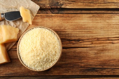 Photo of Bowl with grated parmesan cheese on wooden table, flat lay. Space for text