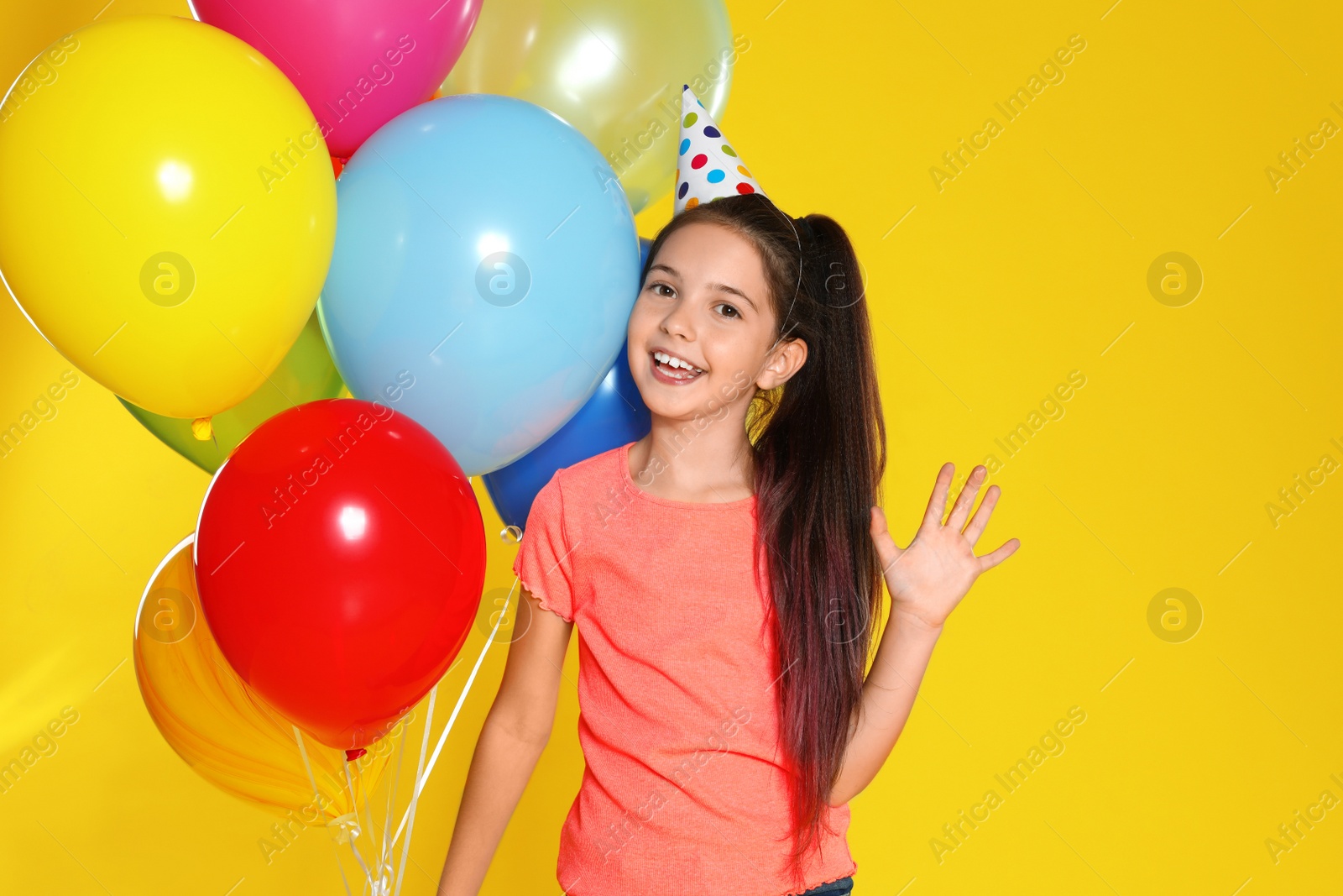 Photo of Happy girl with balloons on yellow background. Birthday celebration