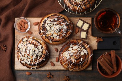 Flat lay composition of delicious rolls with toppings and spices on wooden table. Sweet buns