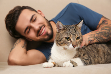 Photo of Happy man with cat on sofa at home. Friendly pet