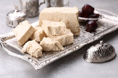 Pieces of tasty halva served on light grey table, closeup