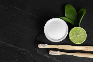 Photo of Bamboo toothbrushes, lemon and bowl of baking soda on black table, flat lay. Space for text