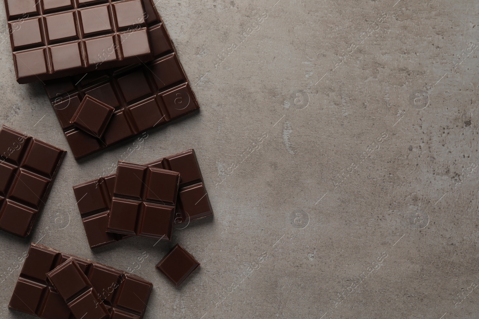 Photo of Delicious dark chocolate on grey table, flat lay. Space for text