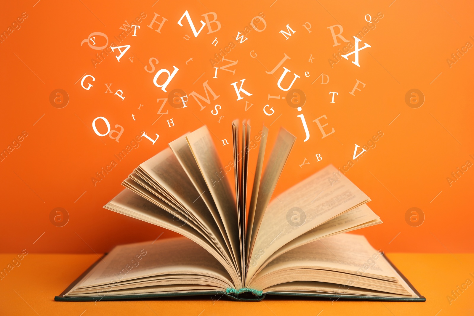 Image of Open book with letters flying out of it on orange background