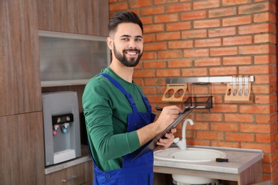 Male plumber with clipboard near kitchen sink. Repair service