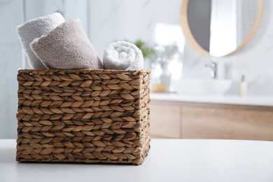 Photo of Wicker basket with clean soft towels in bathroom. Space for text