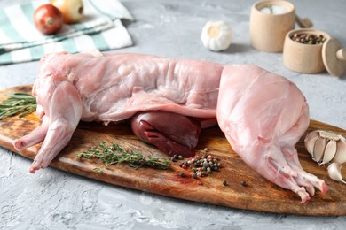 Photo of Whole raw rabbit, liver and spices on grey textured table