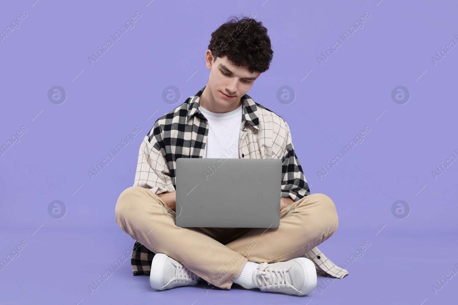 Photo of Portrait of student with laptop sitting on purple background