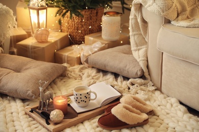 Photo of Wooden tray with cocoa, candle and notebook in room decorated for Christmas