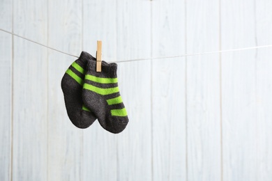 Photo of Pair of socks on laundry line against wooden background, space for text. Baby accessories