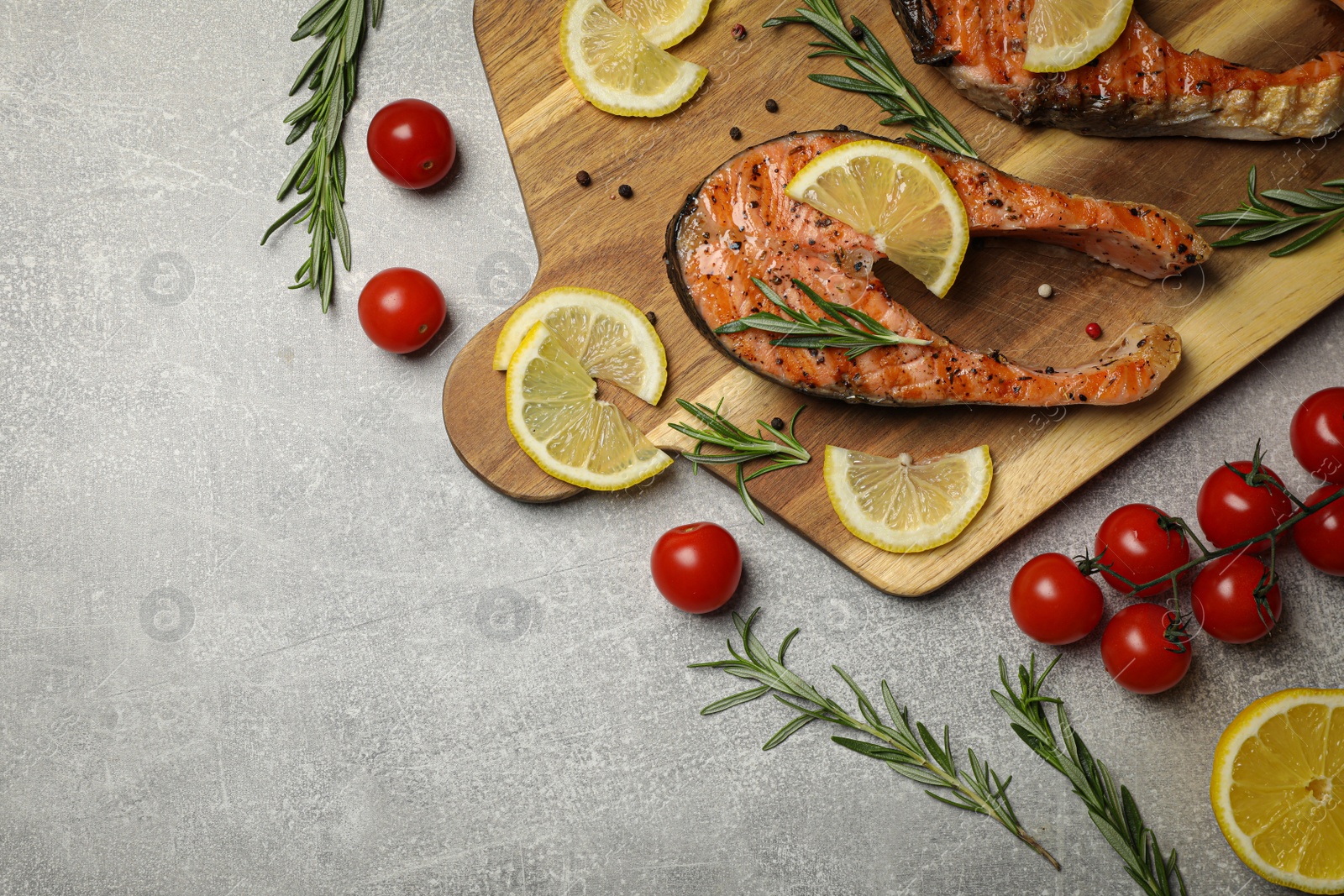 Photo of Tasty grilled salmon steaks and different ingredients on light grey table, flat lay. Space for text