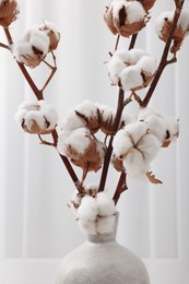 Vase with cotton branches indoors, closeup view