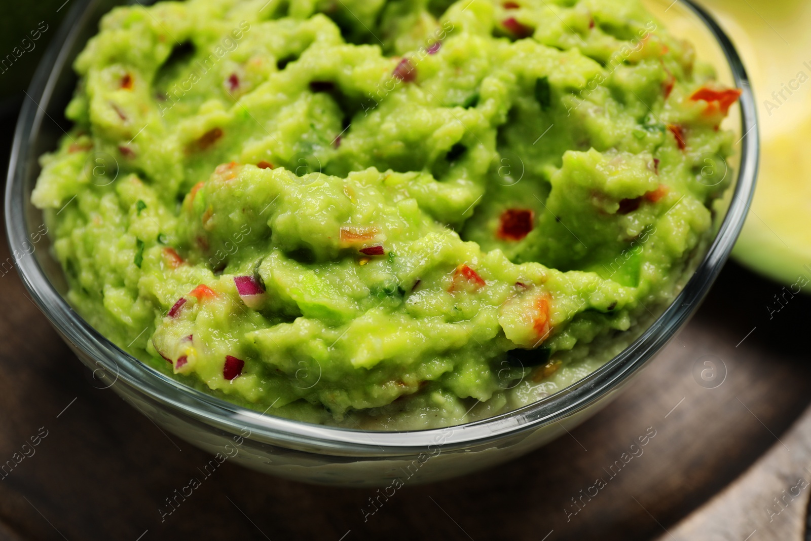 Photo of Glass bowl with delicious guacamole on table, closeup