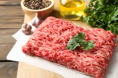 Photo of Raw ground meat, parsley and garlic on wooden table, closeup