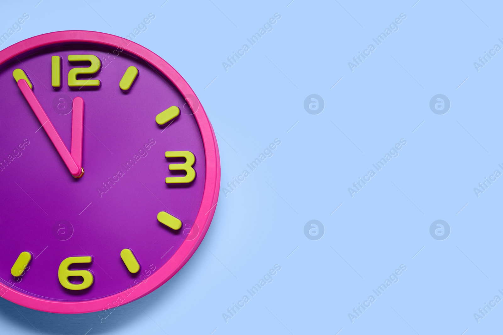 Photo of Clock showing five minutes until midnight on light blue background, top view with space for text. New Year countdown