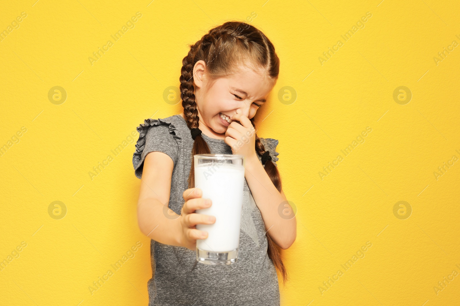 Photo of Little girl with dairy allergy holding glass of milk on color background