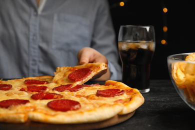 Photo of Woman taking tasty pepperoni pizza at table, closeup