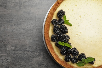 Photo of Delicious cheesecake decorated with blackberries on grey table, top view. Space for text