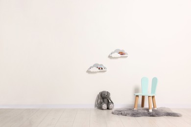 Photo of Beautiful children's room with light wall, chair and toys, space for text. Interior design