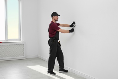 Handyman in uniform working with hammer indoors. Professional construction tools