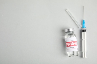 Photo of Vial with coronavirus vaccine and syringe on light background, flat lay. Space for text