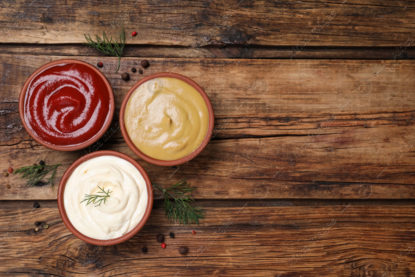 Photo of Many different sauces on wooden table, flat lay. Space for text