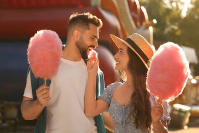 Happy couple with cotton candies at funfair