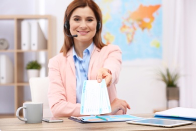 Photo of Beautiful consultant holding tickets in travel agency