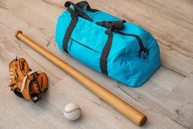 Photo of Sports bag, baseball ball and bat on wooden floor