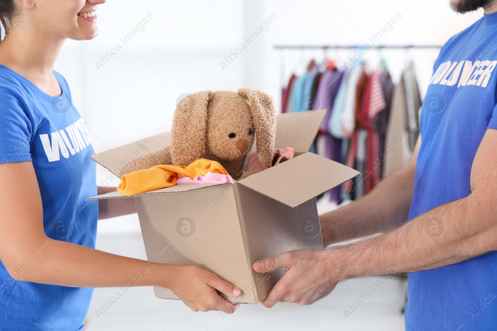 Photo of Young volunteers holding box with donations indoors, closeup