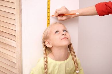 Young woman measuring her daughter's height at home