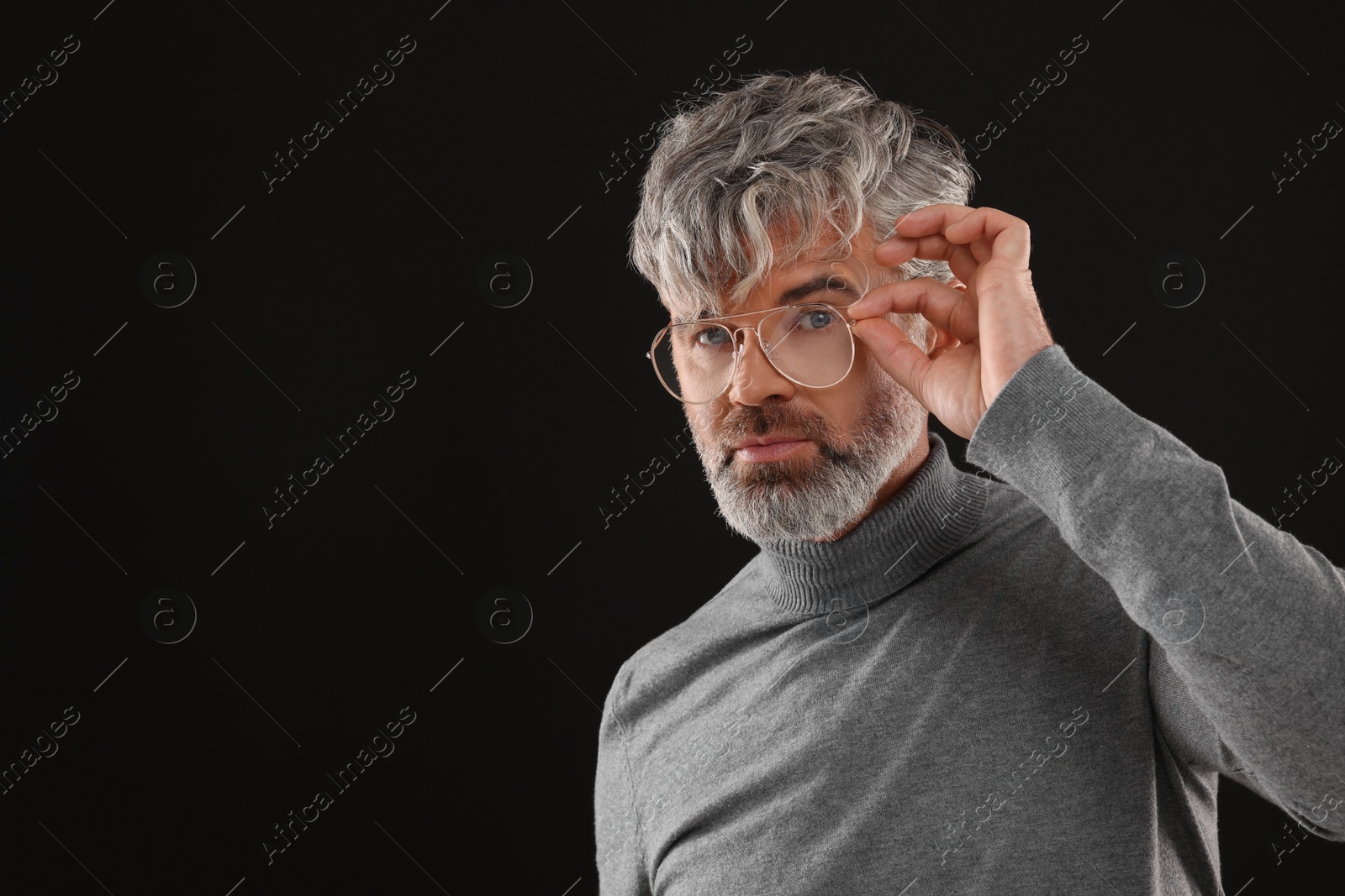 Photo of Portrait of confident man with beautiful hairstyle on black background. Space for text