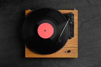 Turntable with vinyl record on black background, top view
