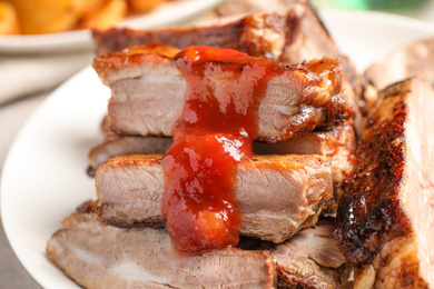 Photo of Delicious grilled ribs with sauce on table, closeup