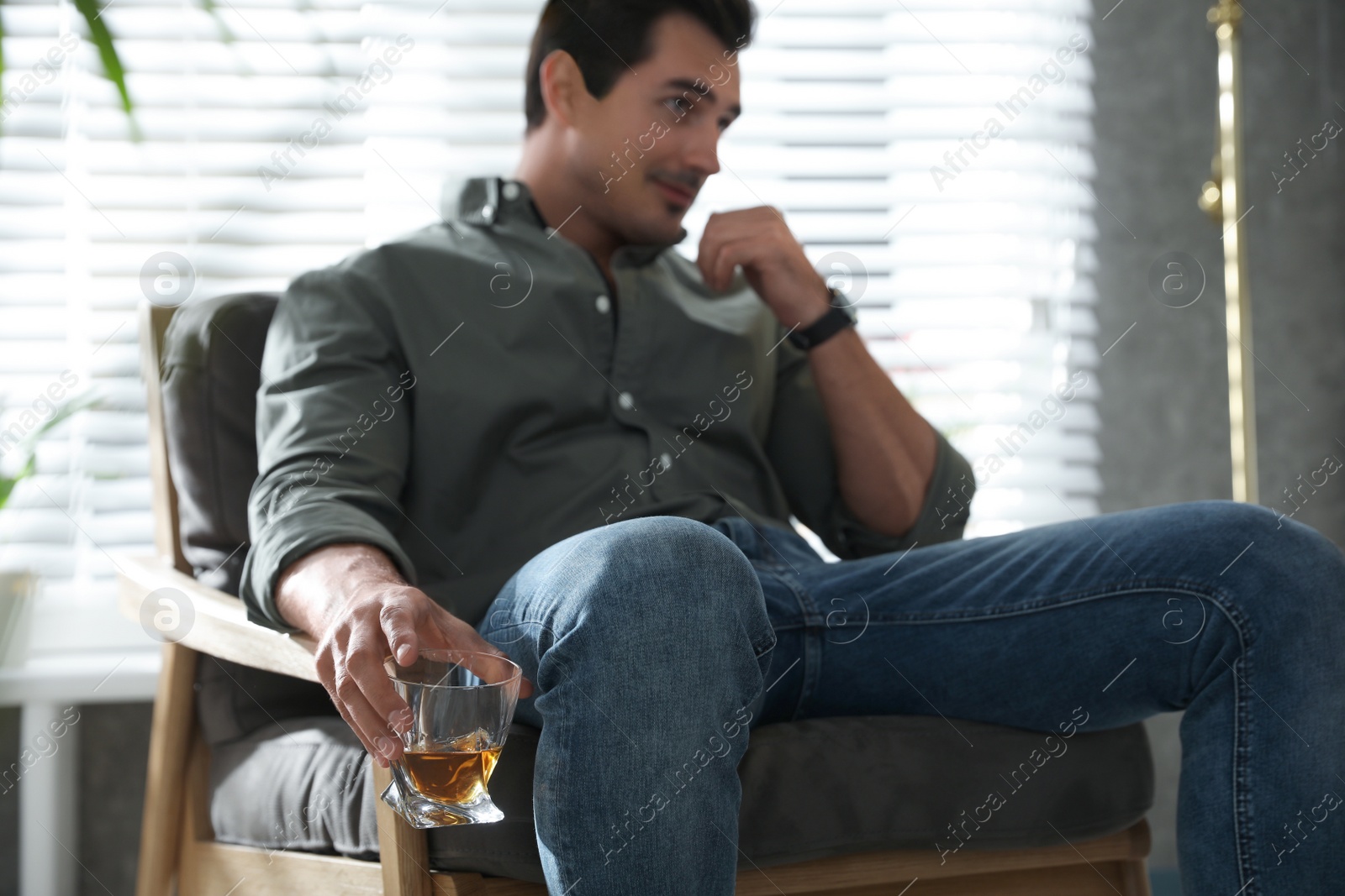 Photo of Young man with glass of whiskey at home