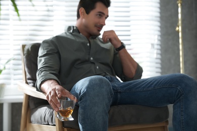 Young man with glass of whiskey at home