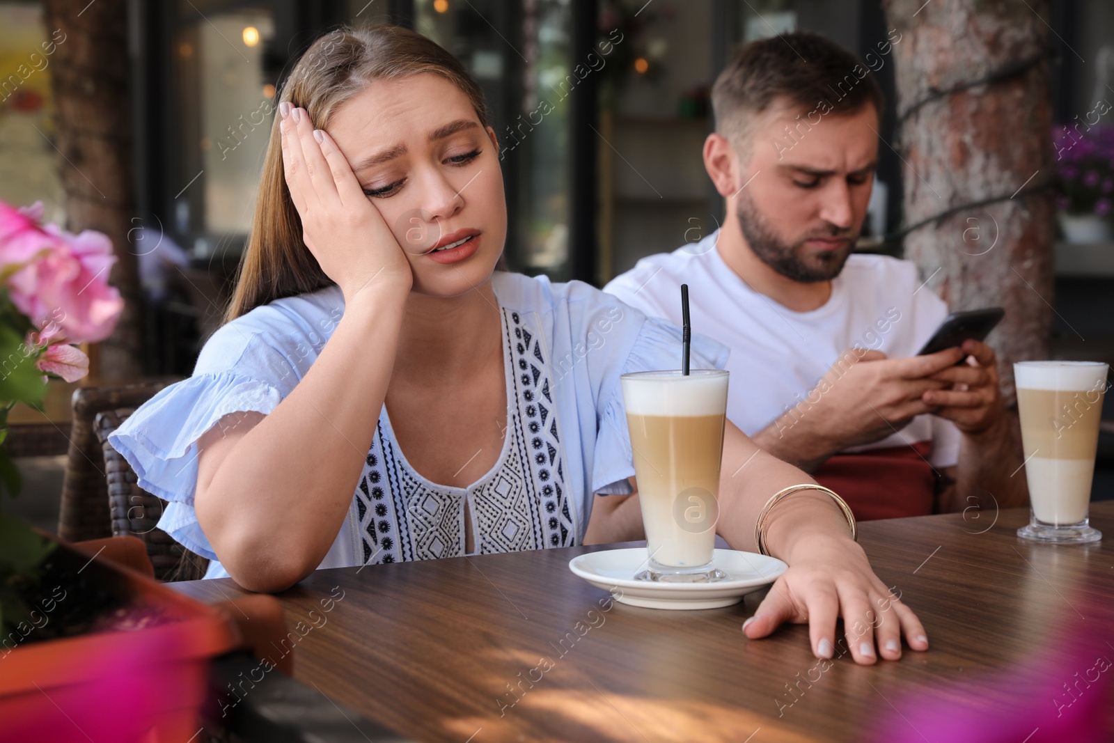 Photo of Young woman having boring date with guy in outdoor cafe