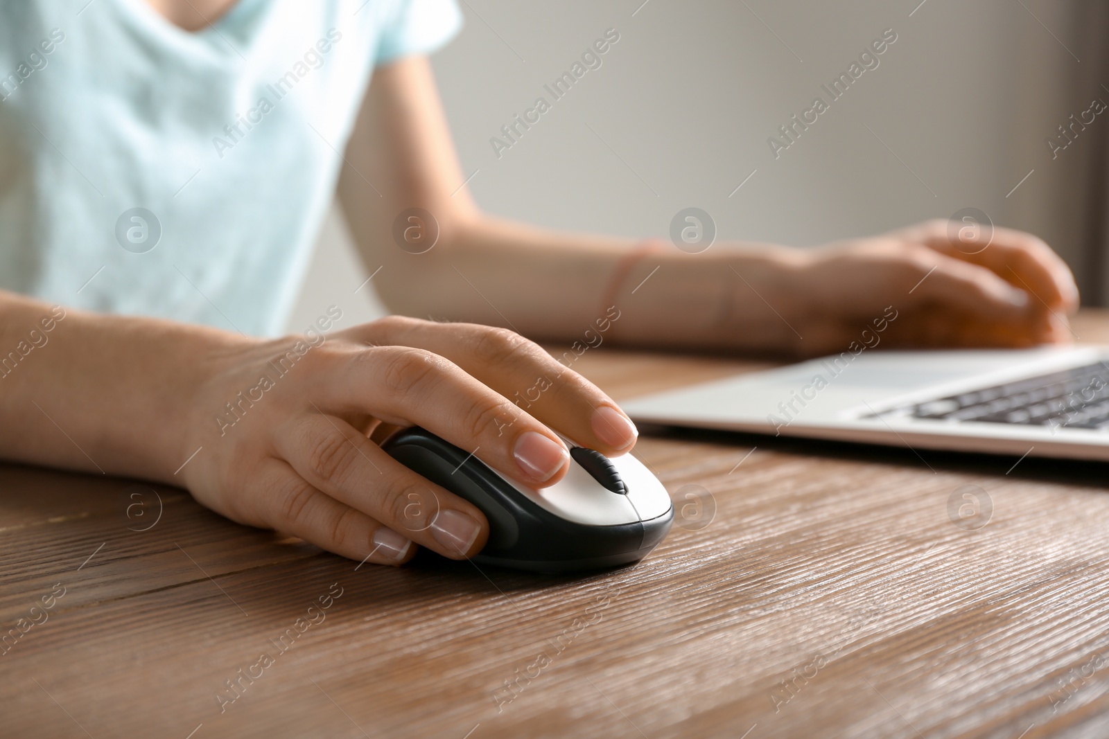 Photo of Woman using computer mouse with laptop at table, closeup